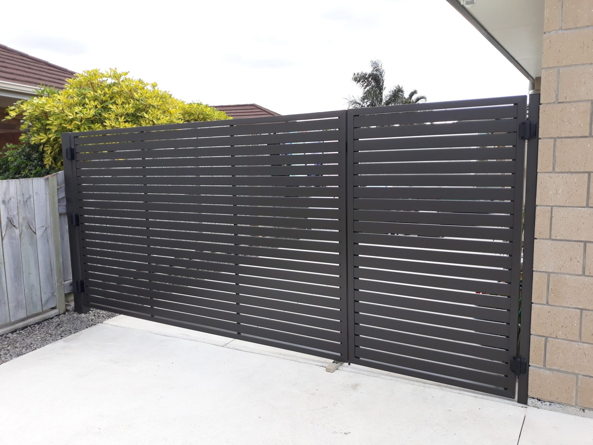 drive way gate one side cars other side people in one gate black horizontal slats
